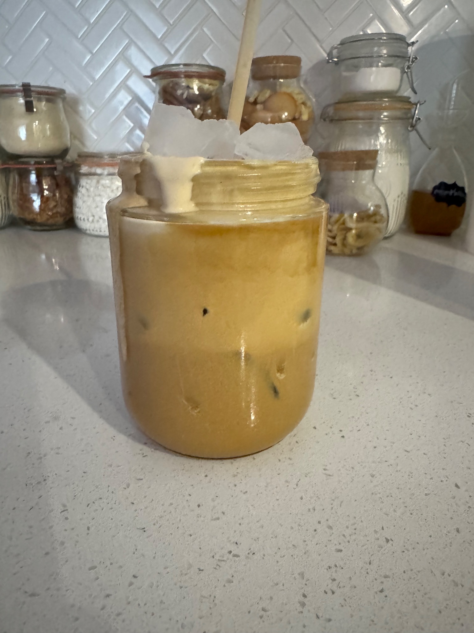 Michelle’s iced coffee in a glass jar, topped with thick golden foam and ice.